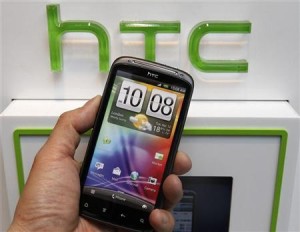 A man poses with a replica of the HTC smartphone inside a mobile phone shop in Taipei